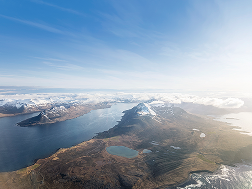 Et luftfoto af en blå flod, der løber gennem et snedækket landskab i de islandske vestfjorde