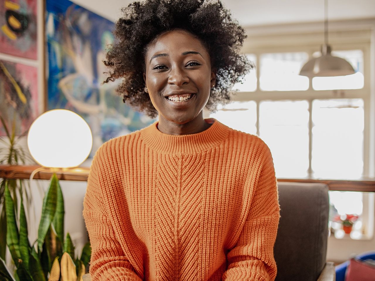 Smiling Black woman in an orange shirt.