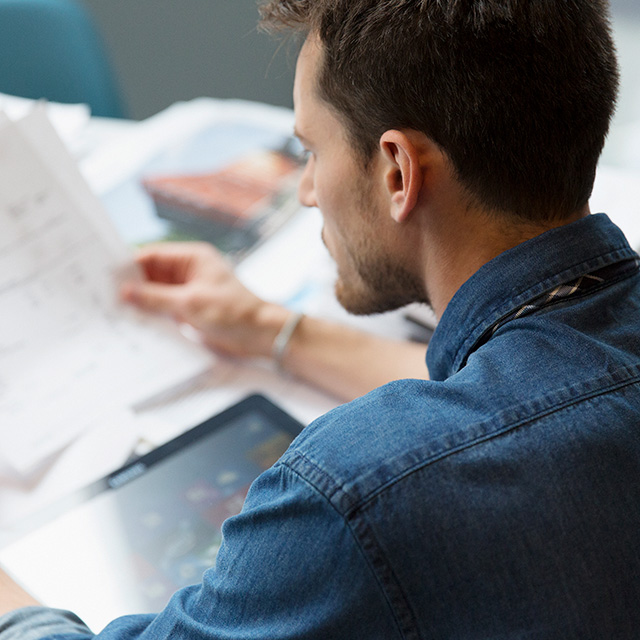White male with dark hair looking at documents at a table.